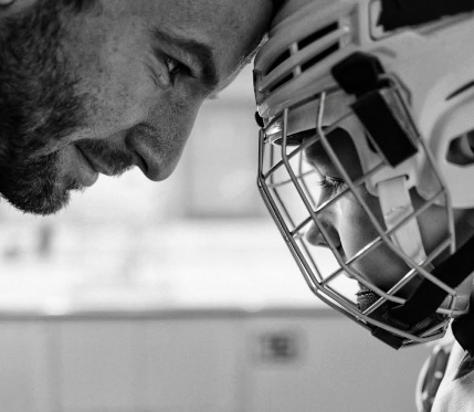 Un jeune hockeyeur casque contre front avec son coach